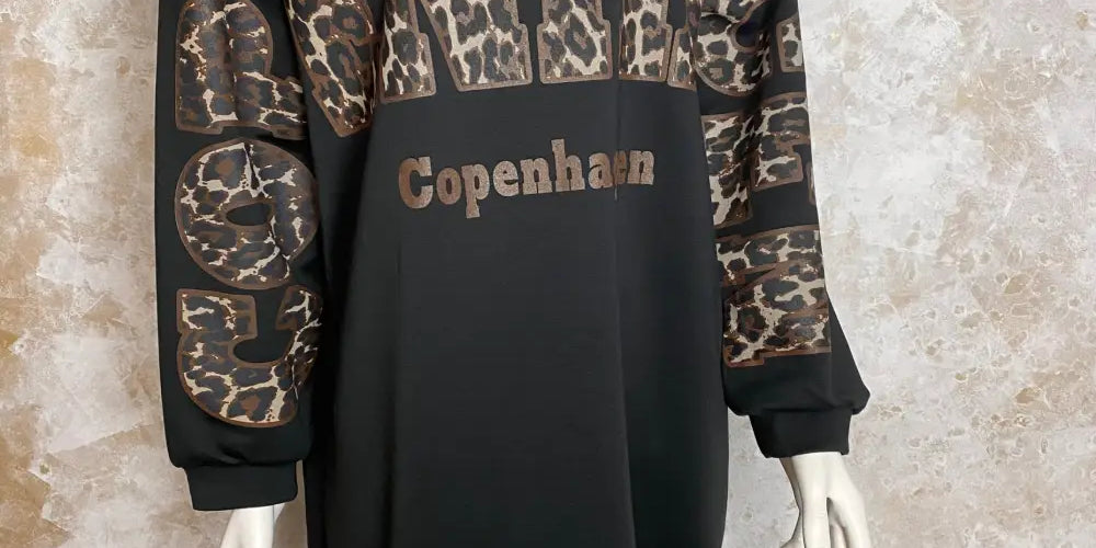 Musta oversized-collegemekko, jossa pehmeä joustava materiaali, Copenhagen-tekstiprintti, pitkät hihat ja lyhyet sivuhalkiot helmassa